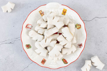 Vegane Anischräbeli im weihnachtlichen Guetzliteller, daneben einzelne Chräbeli – Anisgebäck ohne Ei