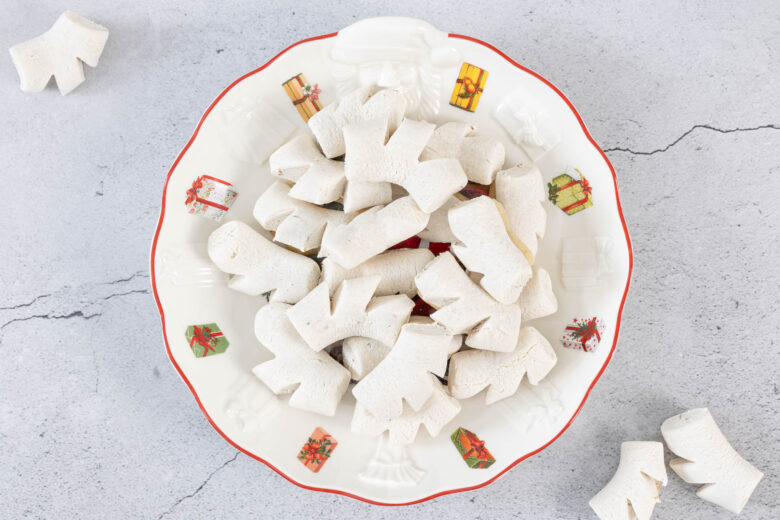 Vegane Anischräbeli im weihnachtlichen Guetzliteller, daneben einzelne Chräbeli – Anisgebäck ohne Ei