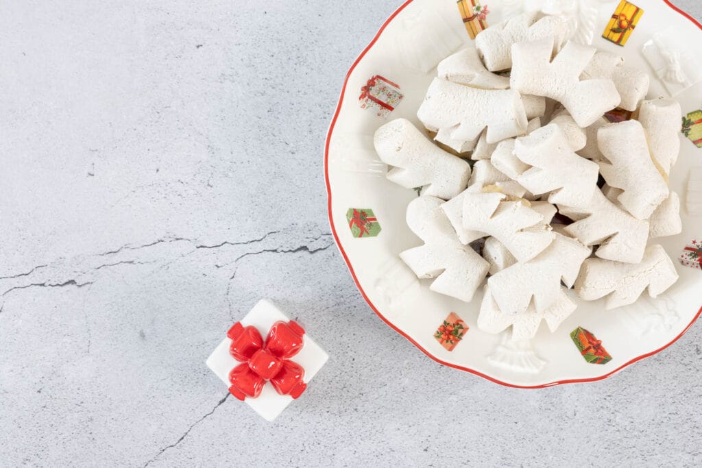 Vegane Anischräbeli auf Weihnachtsteller neben kleinem Porzellangeschenk – aromatische Chräbeli mit Anis