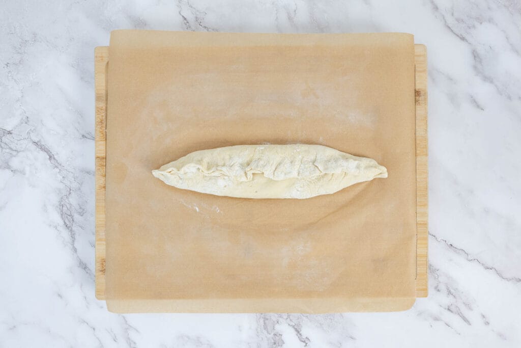 Pide-Teig gefaltet mit hochgeklappten Rändern – klassische Pide-Form entsteht beim Formen