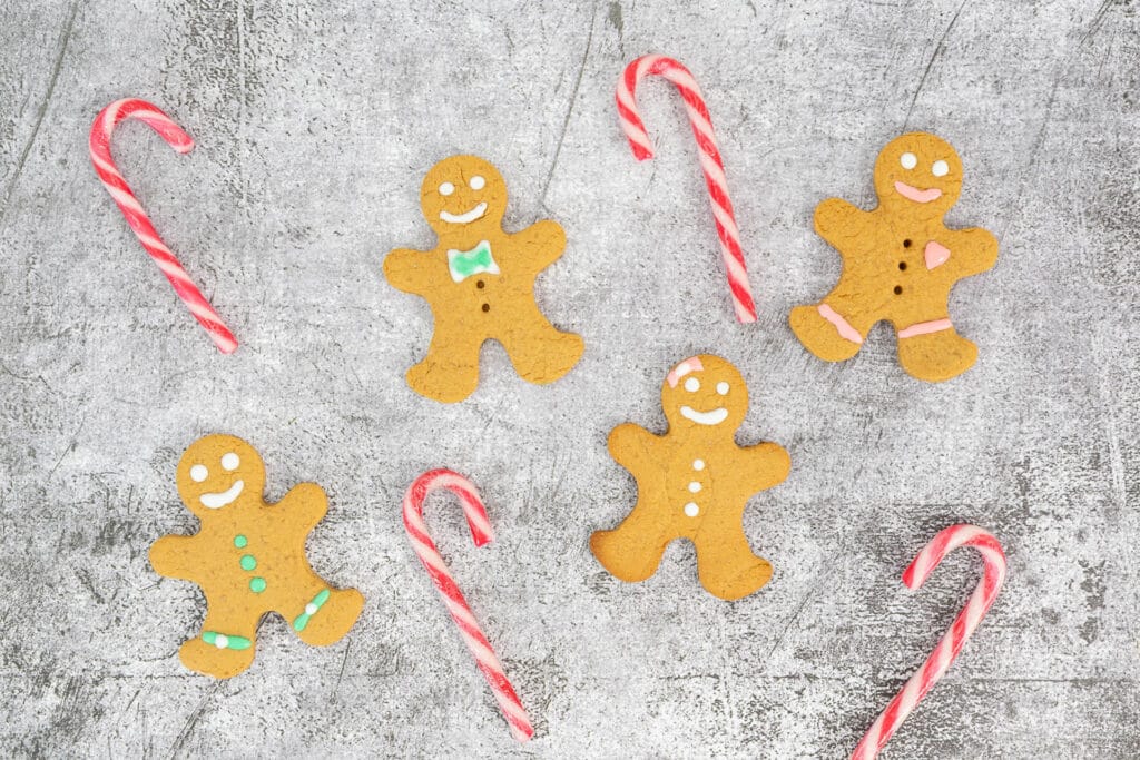 Fünf Gingerbread Men vegan mit Candy Canes auf grauem Untergrund – winterliche Keksdekoration