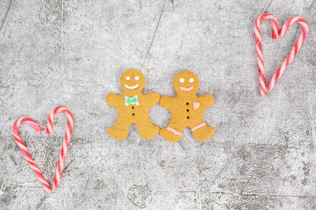 Zwei vegane Gingerbread Men flankiert von herzförmig gelegten Candy Canes – dekoratives Weihnachtsmotiv