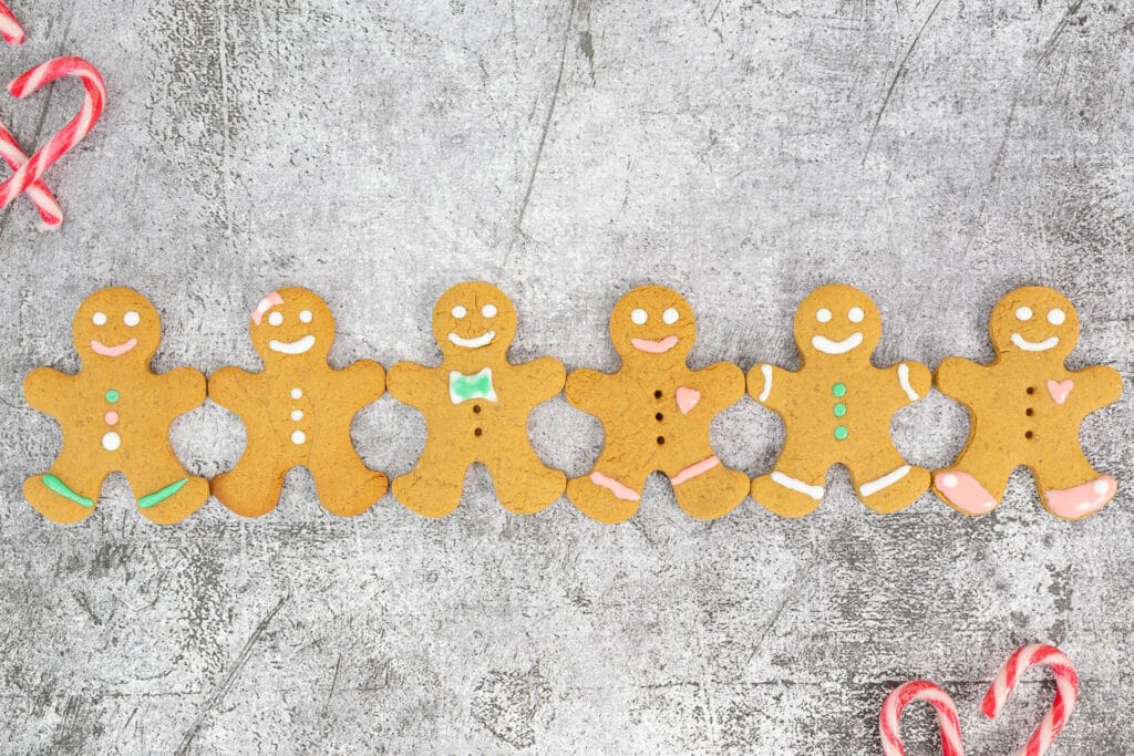 Sechs dekorierte Lebkuchenmännchen vegan in einer Reihe, verziert mit weissem, rosa und grünem Icing