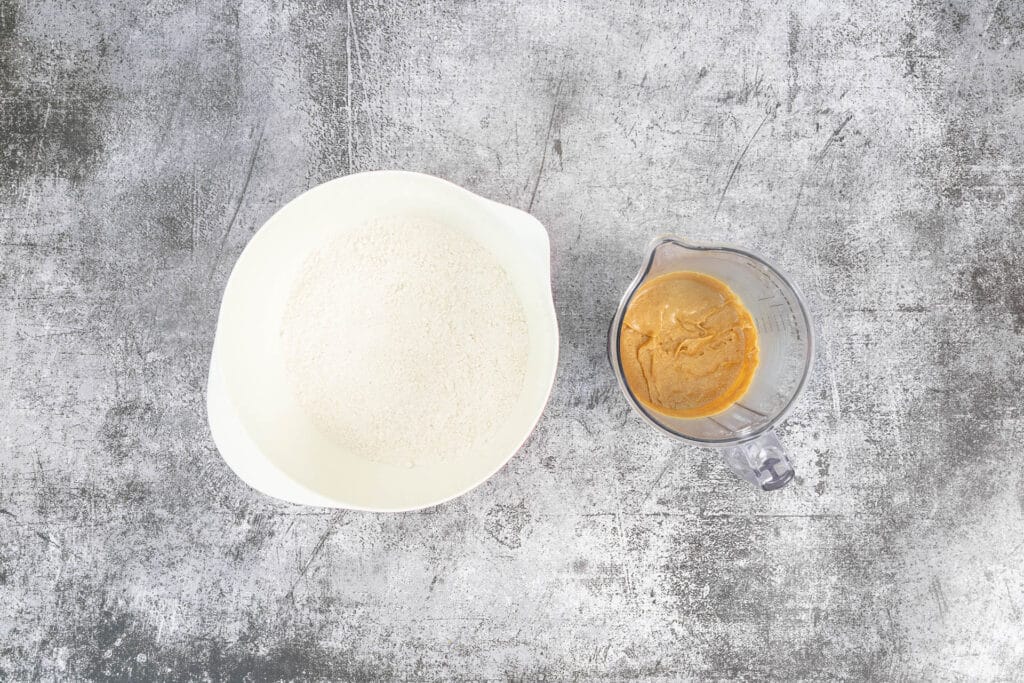 Trockene Zutaten für den veganen Gingerbread-Teig und flüssige Melasse-Zucker-Mischung – Vorbereitung für Lebkuchenmännchen ohne Ei