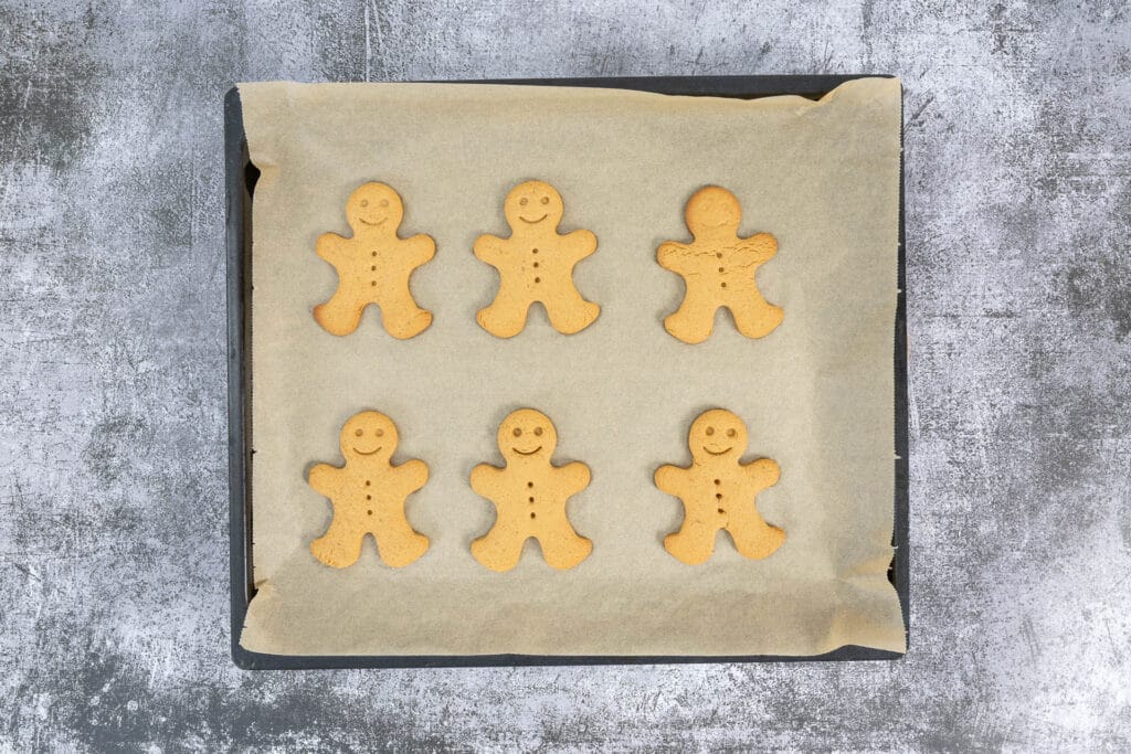 Frisch gebackene Gingerbread Men vegan, leicht gebräunt auf dem Backblech nach dem Backen