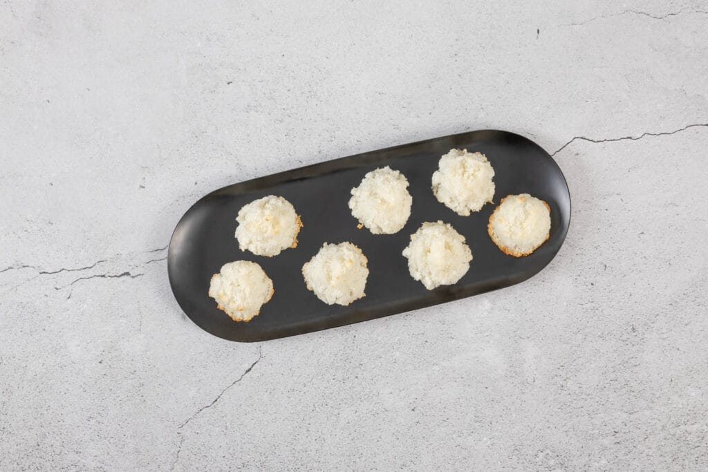 Nahaufnahme der veganen Kokosmakronen auf schwarzer Platte, zart gebacken und ideal als glutenfreie Weihnachtsguetzli