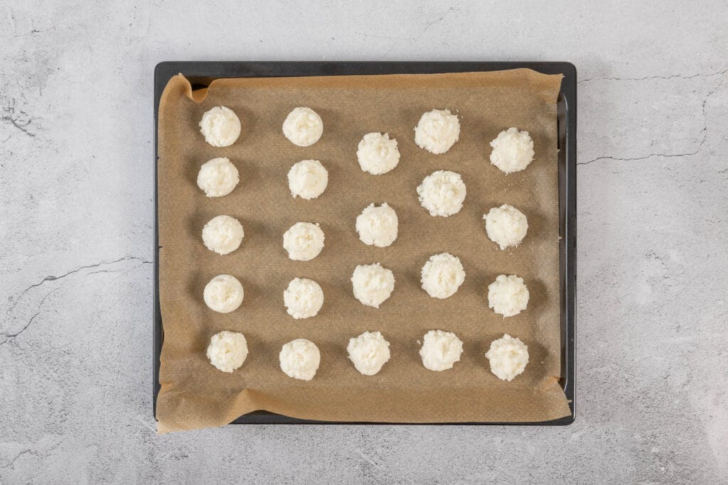 Geformte Kokosmakronen-Häufchen roh auf Backpapier, vorbereitet für das vegane Weihnachtsguetzli-Rezept