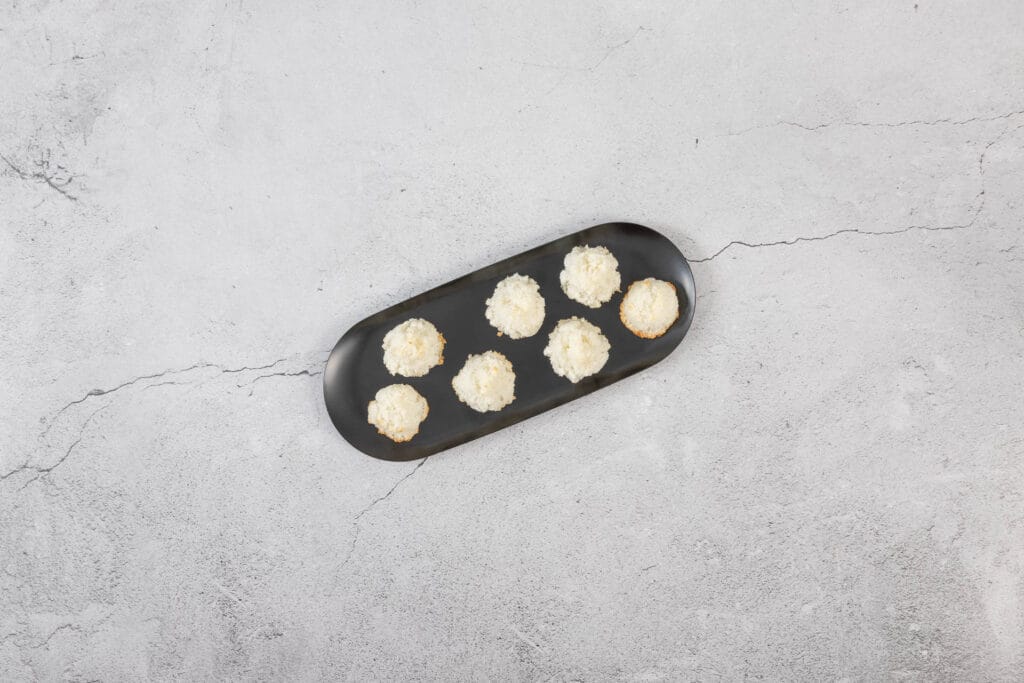 Vegane Kokosmakronen angerichtet auf schwarzer Platte als zarte, glutenfreie Weihnachtsguetzli