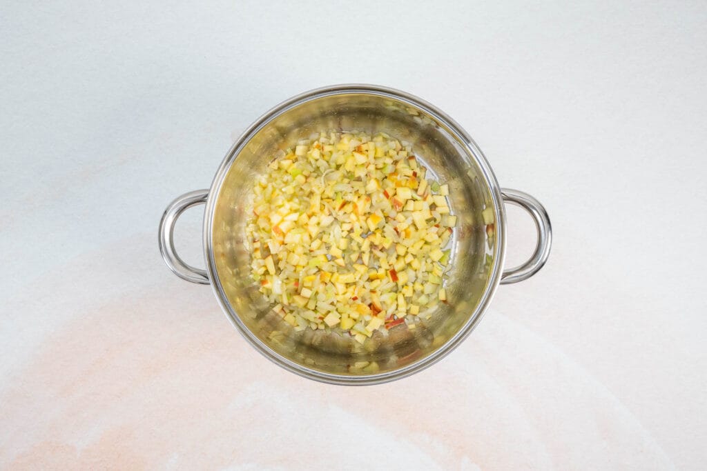 Apfel- und Zwiebelwürfel werden im Topf angedünstet als Basis für klassisches Rotkraut Rezept