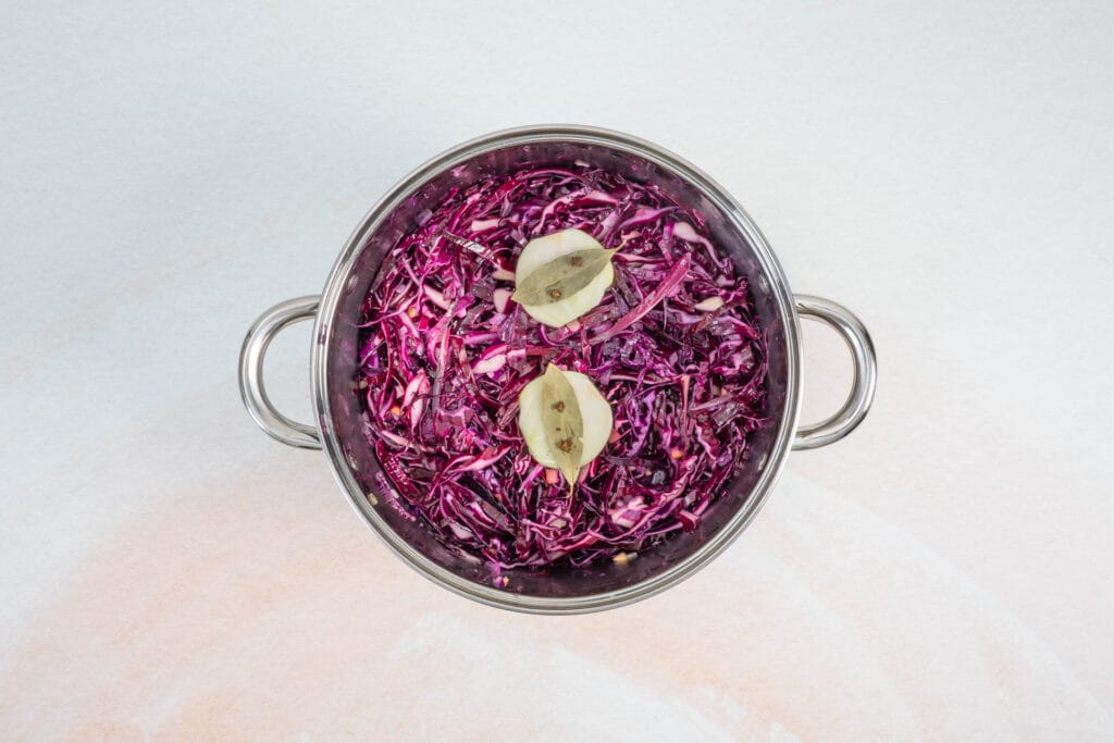 Rotkohl im Topf mit gespickter Zwiebel und Lorbeerblättern vor dem Schmoren für veganes Rotkraut