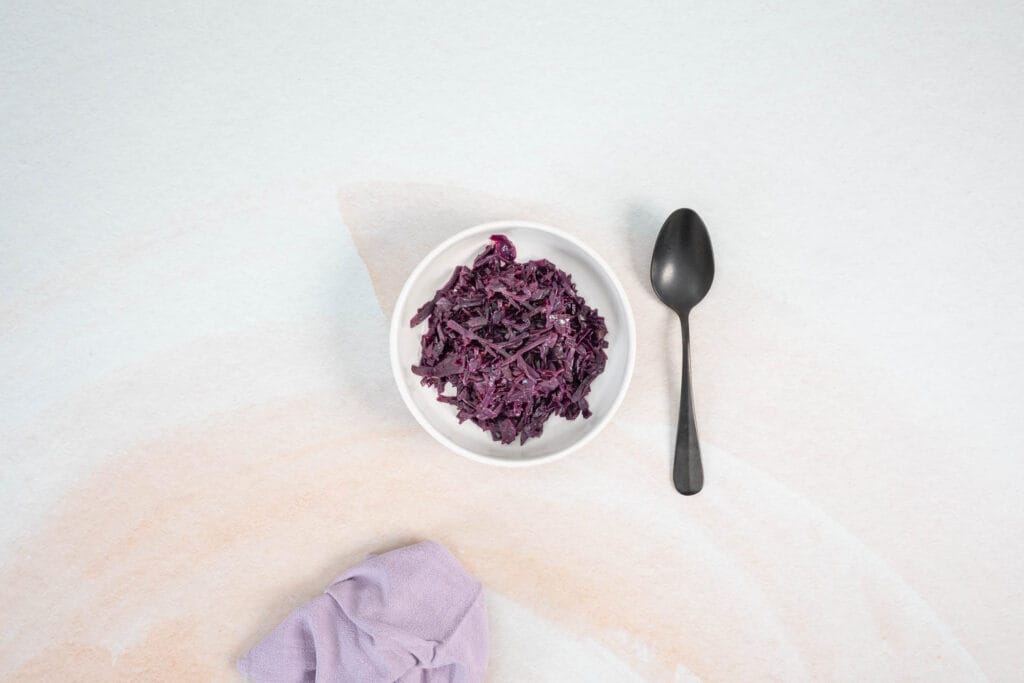Serviertes veganes Rotkraut in einer kleinen weissen Schale mit Löffel als klassische Beilage