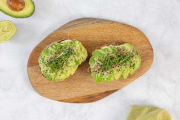 Avocado-Toast mit Sauerteigbrot, Limette und frischen Sprossen als gesundes veganes Frühstück