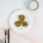 Knusprige vegane Zucchetti-Puffer mit frischem Joghurt-Dip angerichtet als einfaches Hauptgericht