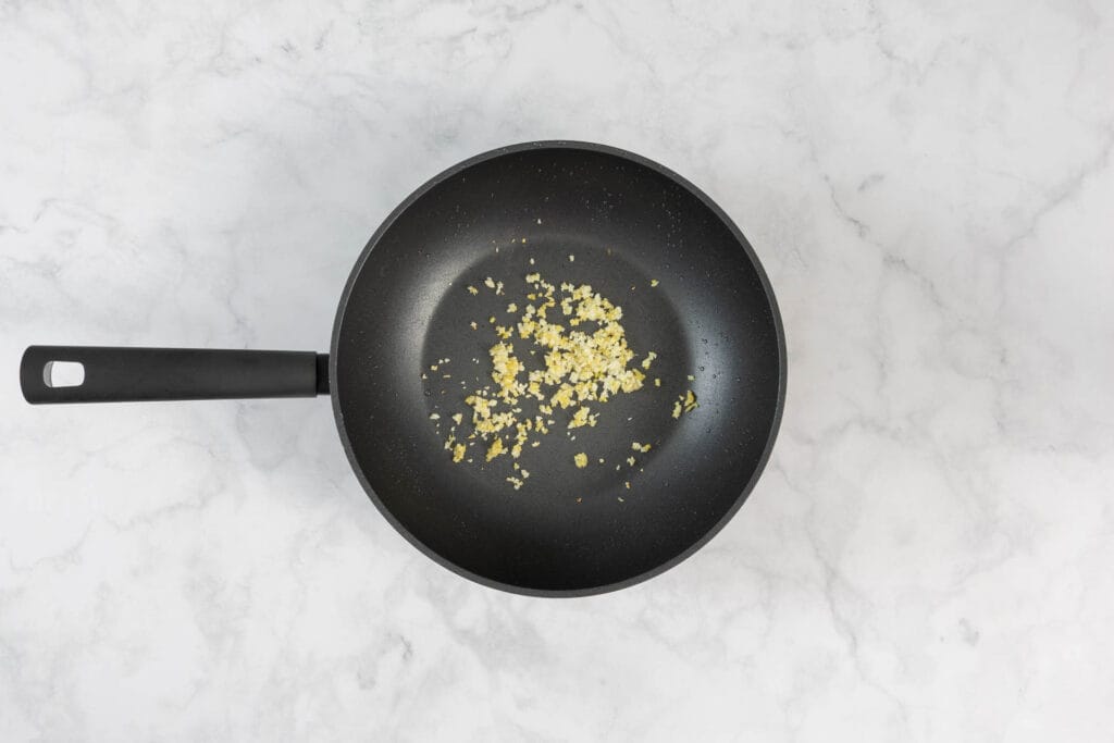 Knoblauch und Ingwer in der Pfanne für die Orangensauce andünsten