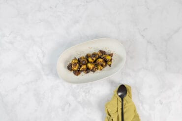 Gerösteter Rosenkohl aus dem Ofen angerichtet auf einer hellen Platte