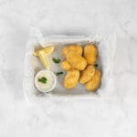 Knusprige vegane Fischknusperli mit Tartarsauce und Zitrone serviert