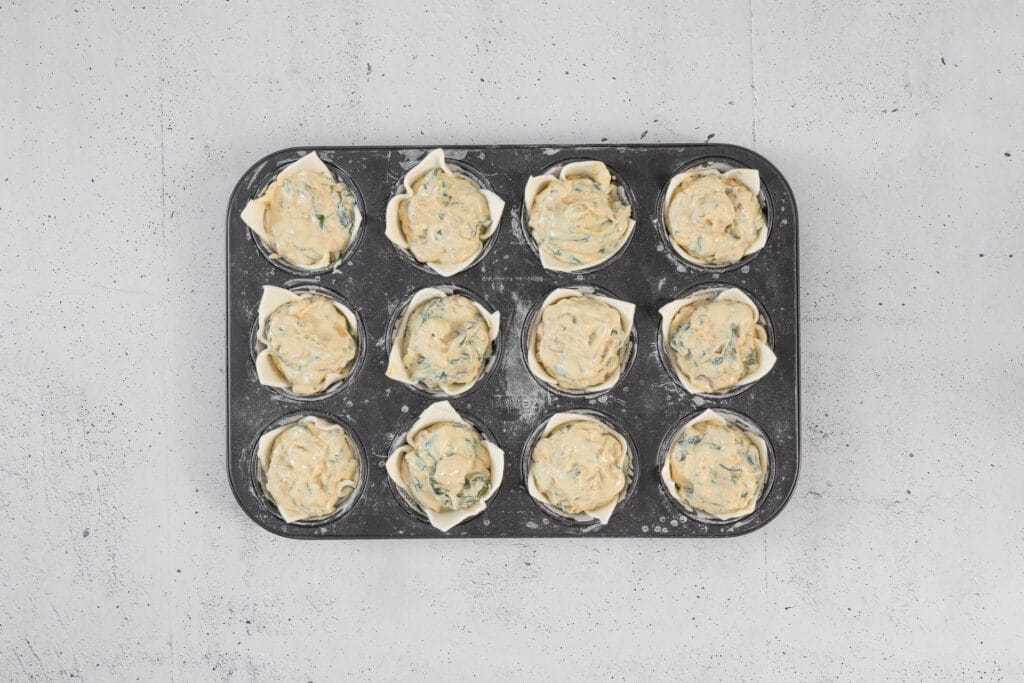 vegane Quiche Muffins ungebacken mit Füllung in Muffinform bereit für den Ofen