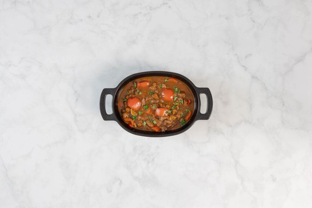 Fertiges veganes Gulasch mit Paprika und Petersilie in einer Servierschale