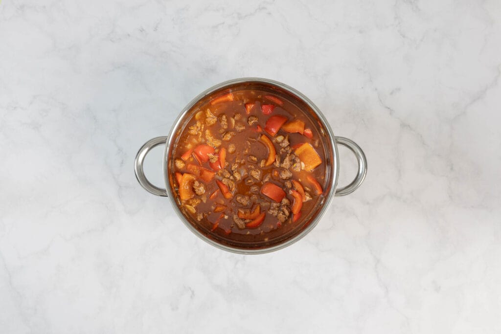 Veganes Gulasch mit Paprika und Sojaschnetzeln im Topf vor dem Schmoren