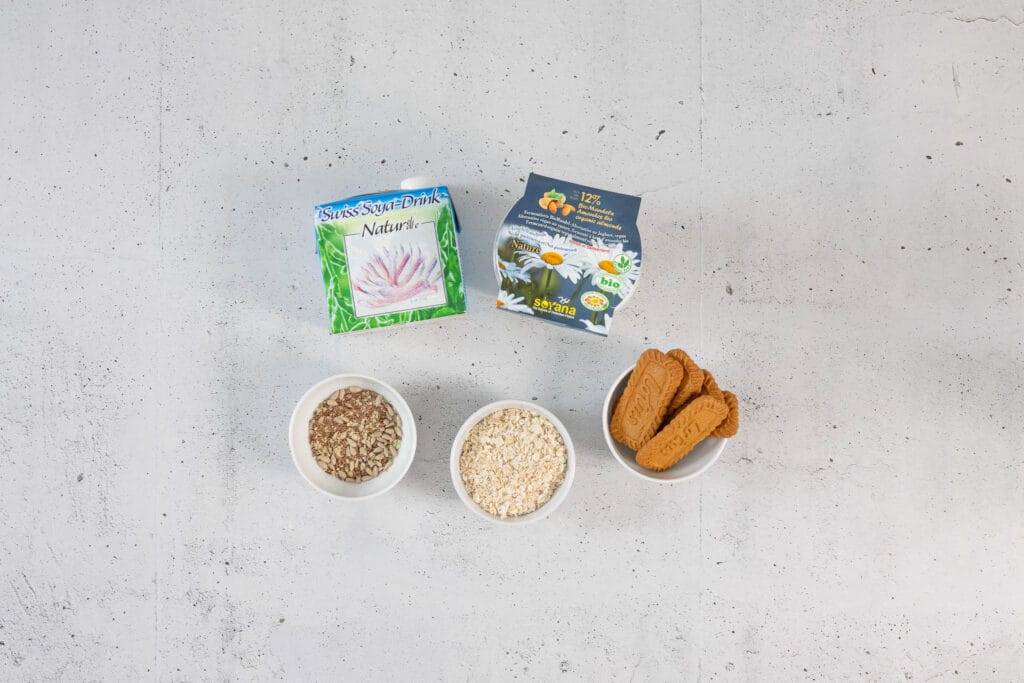 Zutaten für vegane Overnight Oats Japanese Cheesecake mit Soyana Soya-Drink, Mandel-Joghurt und Lotus Biscoff