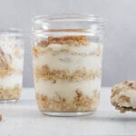 Cremige vegane Overnight Oats Japanese Cheesecake mit Löffel und Lotus Biscoff Biscuits im Glas