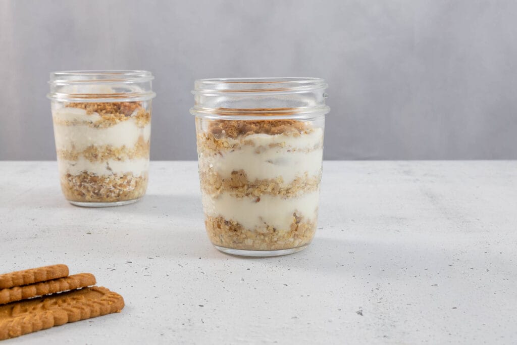 Veganes Frühstücks-Rezept im Glas mit cremigen Schichten und Lotus Biscoff Biscuits daneben