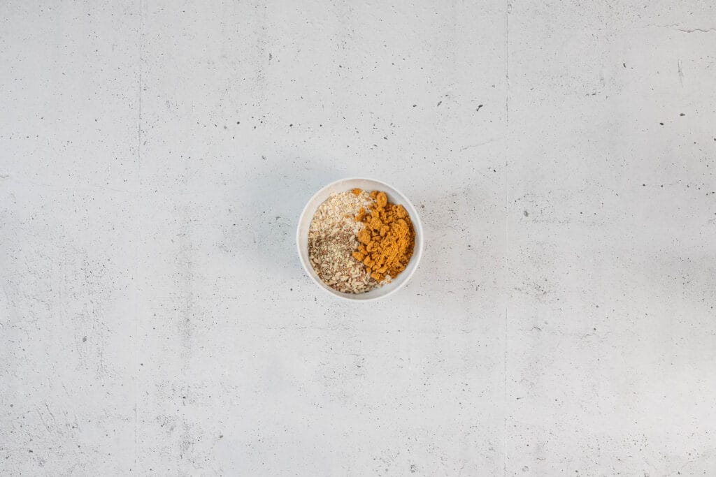 Haferflocken, Nuss-Samen-Mischung und Lotus Biscoff Brösel in einer Schüssel als Basis für das Frühstücks-Rezept