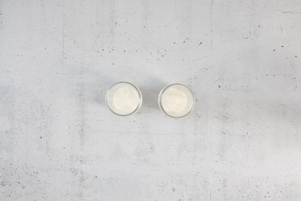 Erste Schicht pflanzliches Joghurt in den Einmachgläsern für die Zubereitung des veganen Frühstücks-Rezepts
