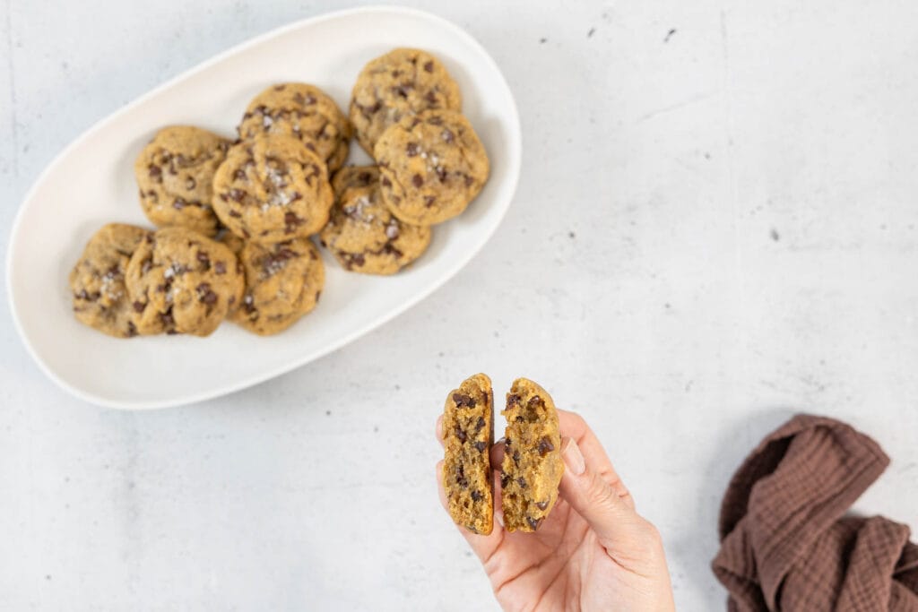 Aufgebrochener Chocolate Chip Cookie in der Hand zeigt die chewy Innentextur – so sieht ein echtes amerikanisches Cookie aus