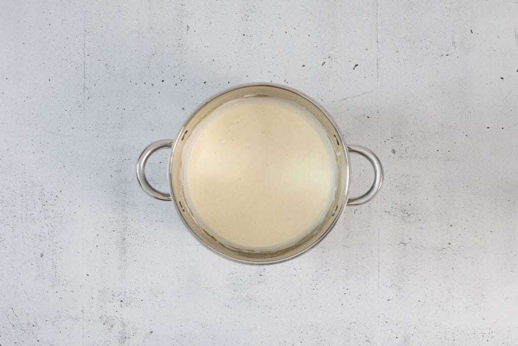 Cremige Sauce aus Mehlschwitze und pflanzlichem Rahm im Topf, Zwischenschritt der veganen Kapernsauce