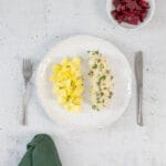 Nahaufnahme der veganen Königsberger Klopse mit Kapernsauce und Petersilie auf Salzkartoffeln