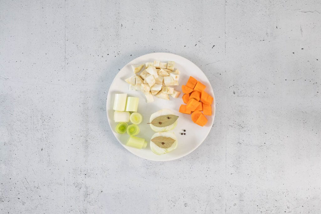 Grob geschnittenes Gemüse für die selbstgemachte Klopsbrühe: Sellerie, Karotte, Lauch, Zwiebel, Lorbeerblätter und Pfefferkörner