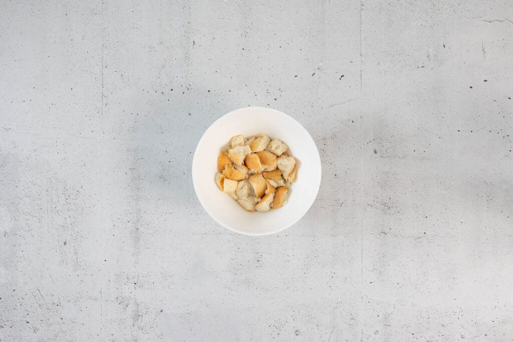 Ausgedrücktes und leicht zerrissenes eingeweichtes Brötchen in einer Schale – Zwischenschritt für die Klopsmasse