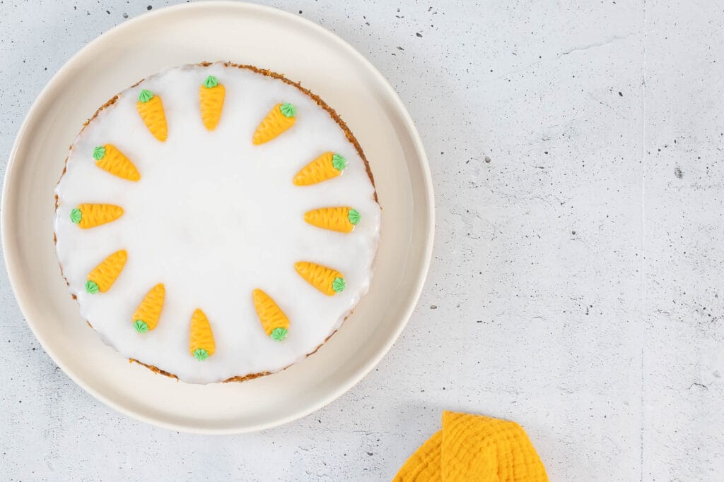 Vegane Aargauer Rüeblitorte mit Glasur auf Teller und gelber Serviette