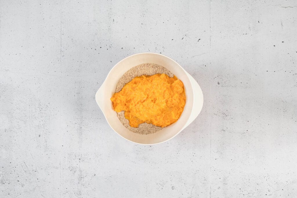 Karottenmasse wird zu trockenen Zutaten für vegane Rüeblitorte gegeben