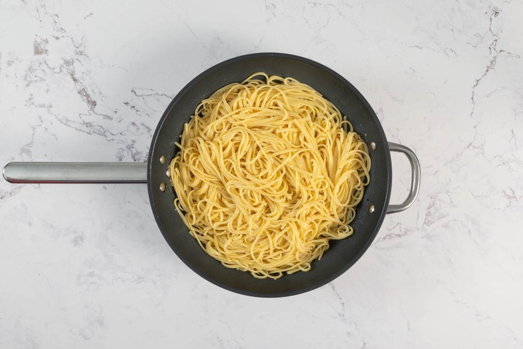 Al dente gekochte Linguine in der Pfanne mit der Weissweinsauce vermengt für die vegane Muschelpasta