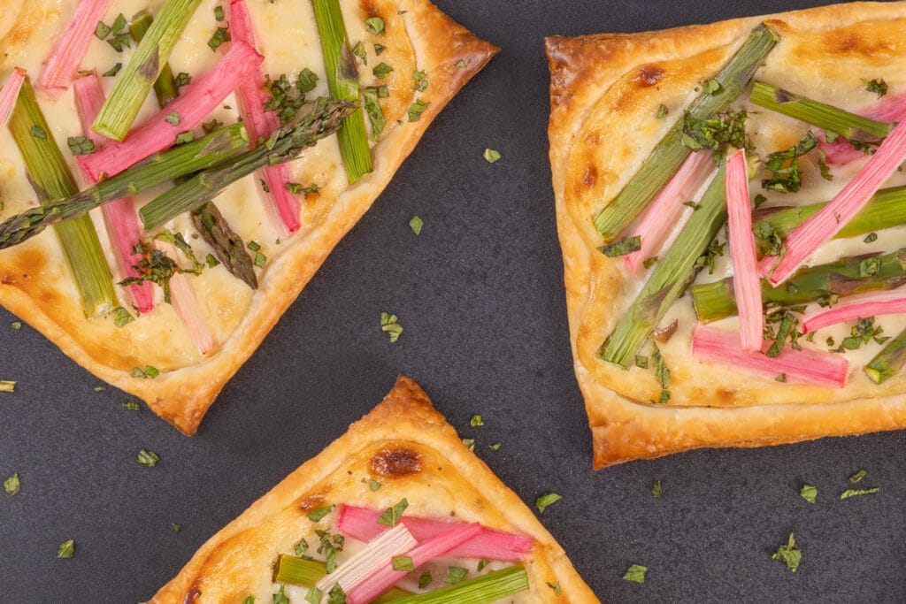 Detailaufnahme der herzhaften Spargel-Rhabarber-Tartelettes mit veganer Frischkäsemasse und frischer Minze