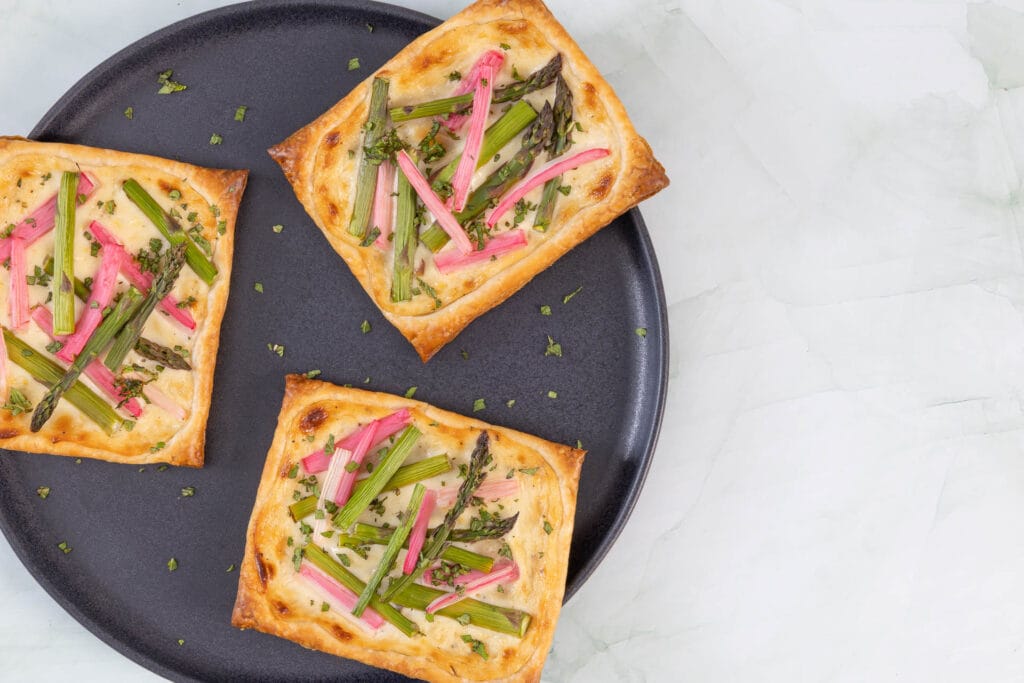 Drei servierte Spargel-Rhabarber-Tartelettes als veganes Frühlingsrezept mit grünem Spargel und Rhabarber