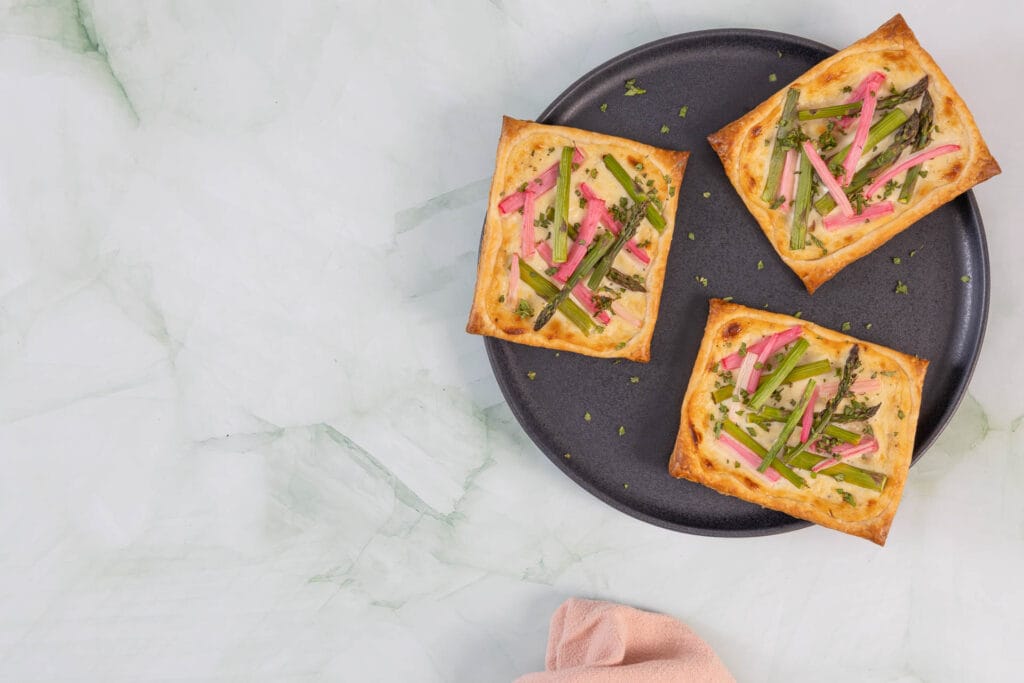 Vegane Frühlingstartelettes mit Spargel, Rhabarber und veganem Rahmfrischkäse auf rundem Teller