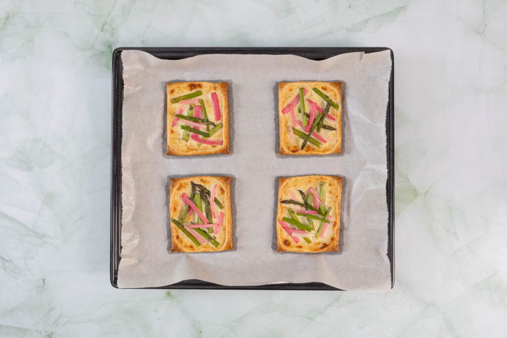 Vegane Spargel-Rhabarber-Tartelettes nach dem Backen, goldbrauner Blätterteig mit grünem Spargel und Rhabarber