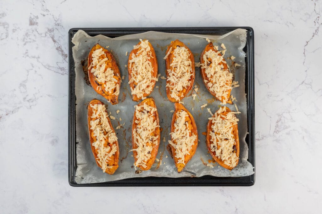 Gefüllte Süsskartoffeln vegan mit veganem Käse bestreut vor dem Überbacken im Ofen