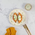 Gefüllte Süsskartoffeln vegan mit Bohnenfüllung, Sauerrahm und Kräutern auf dem Teller