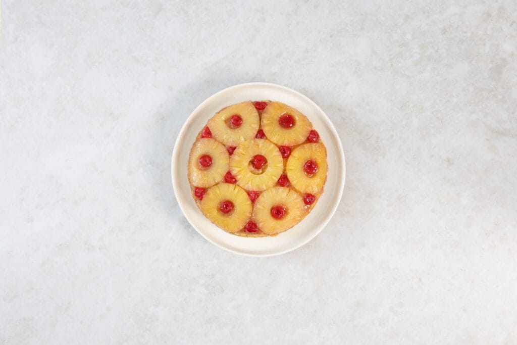 Frisch gestürzter veganer Ananaskuchen mit glänzender Ananas und Cocktailkirschen von oben