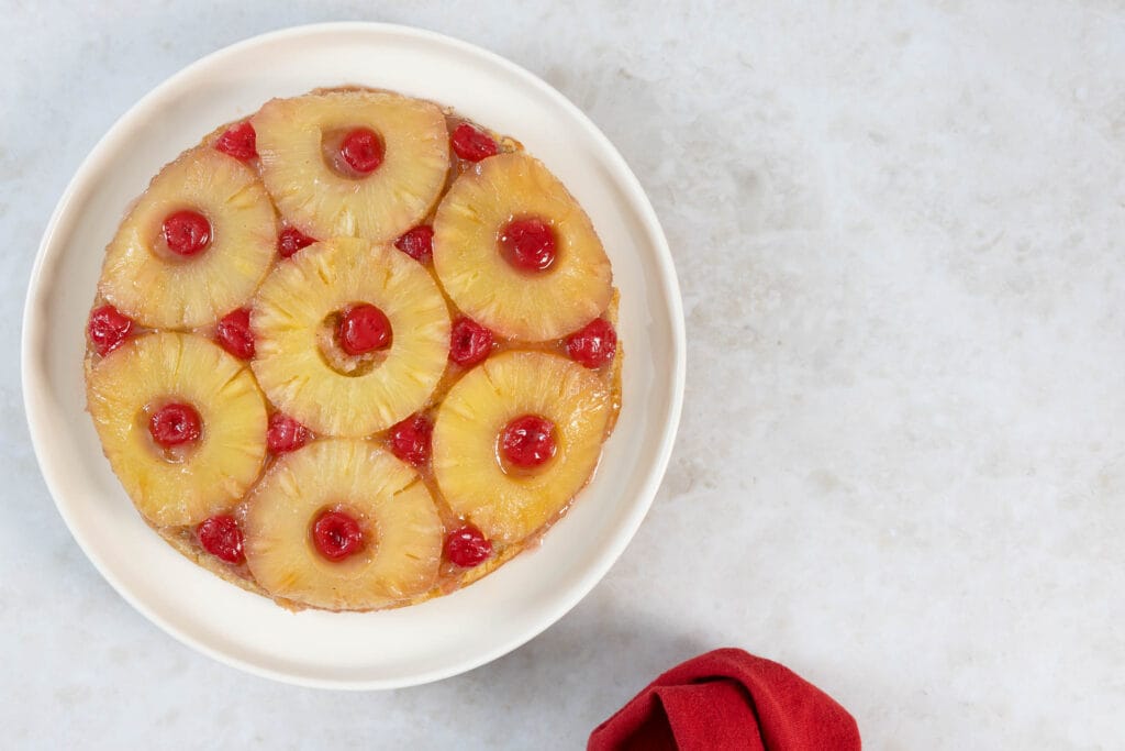 Gestürzter Ananaskuchen auf hellem Teller mit roter Serviette daneben