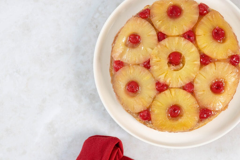 Veganer gestürzter Ananaskuchen auf dem Teller, angerichtet mit roter Stoffserviette
