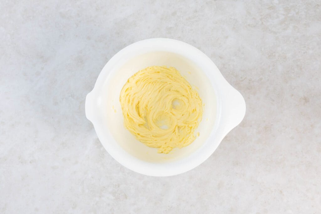 Weiche vegane Butter cremig aufgeschlagen in einer Rührschüssel für den Teig des Ananaskuchens