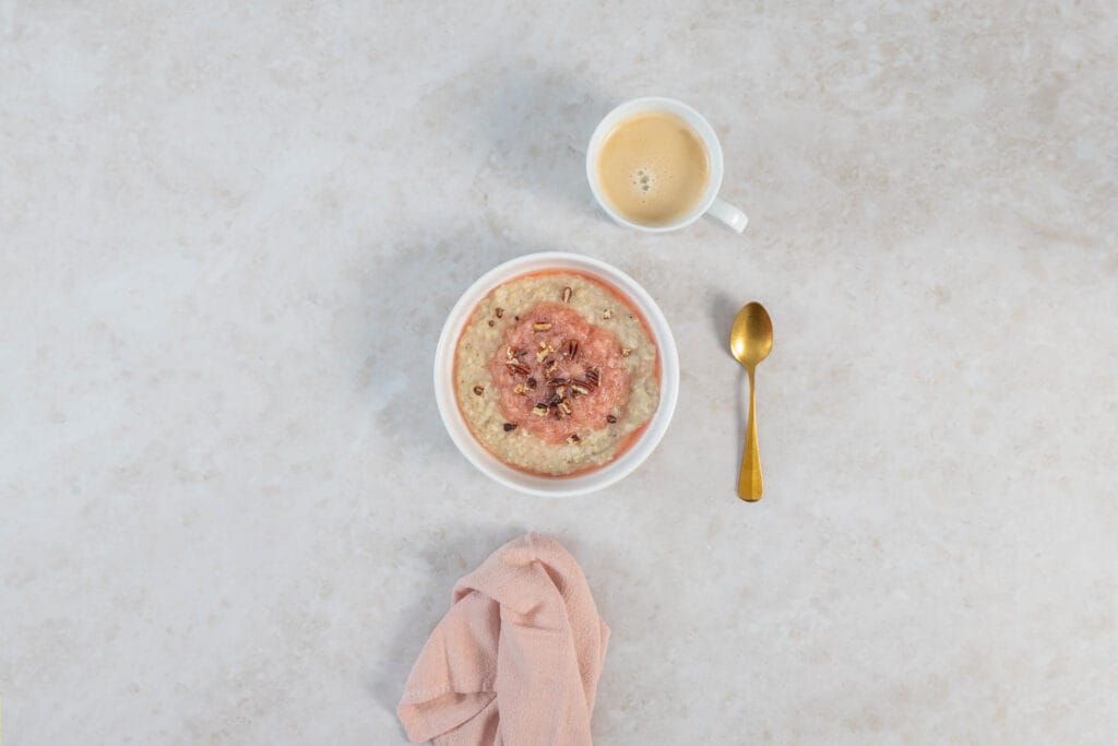 Veganes Frühlingsfrühstück mit Rhabarber-Porridge, dazu eine Tasse Kaffee und ein Leinentuch