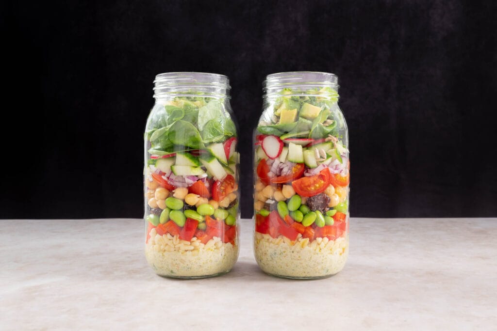 Proteinreicher veganer Salat im Glas zum Mitnehmen mit sichtbaren bunten Schichten