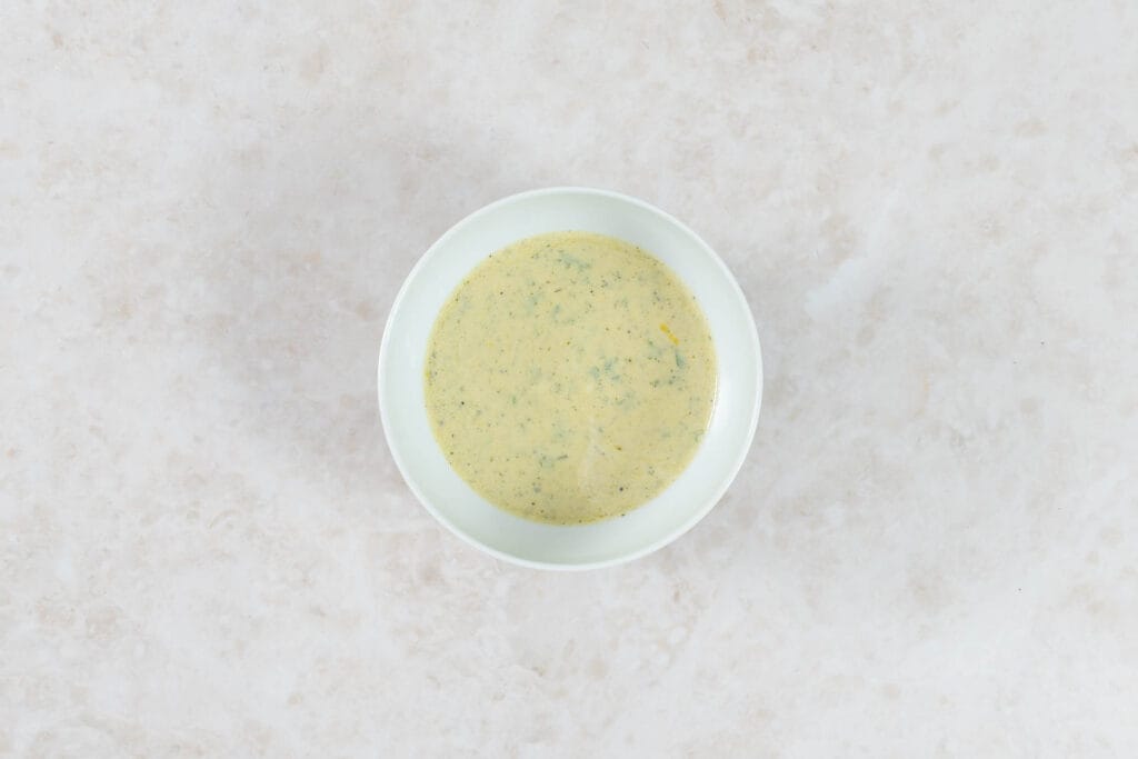 Fertig verrührtes veganes Zitronen-Joghurt-Dressing für den Salat im Glas