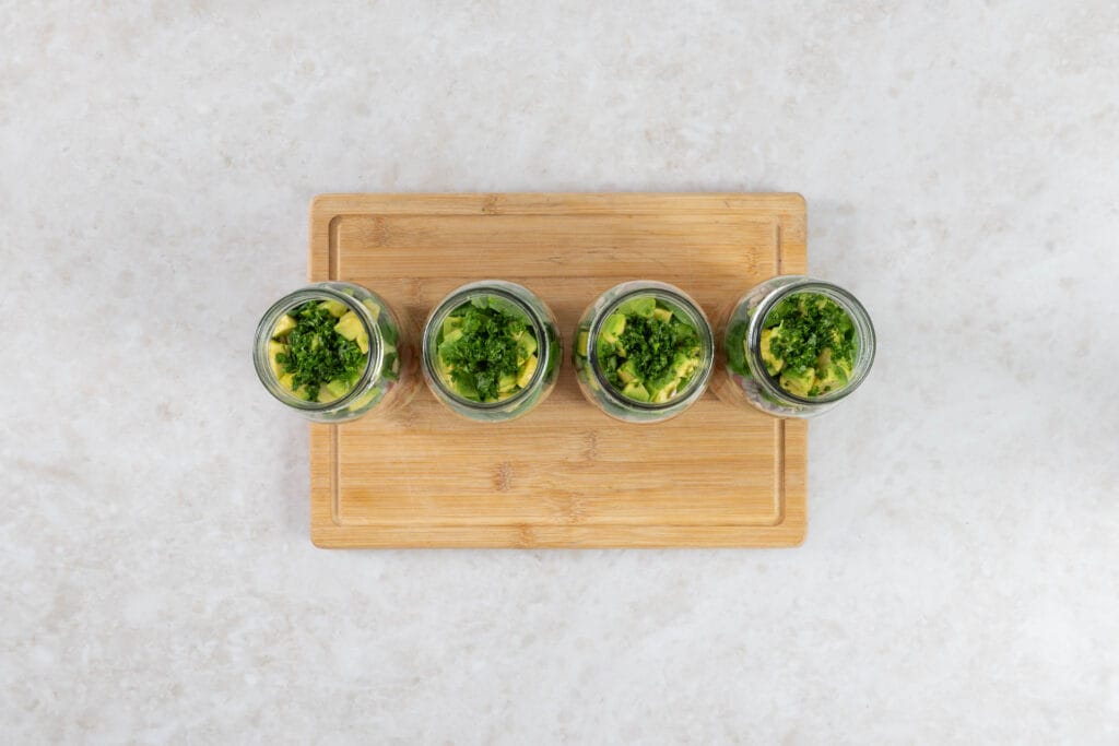 Veganer Salat im Glas mit Avocado, Petersilie und Koriander als oberste Schicht
